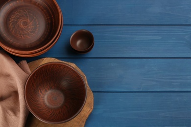 Photo of Set of clay utensils on blue wooden table, flat lay. Space for text