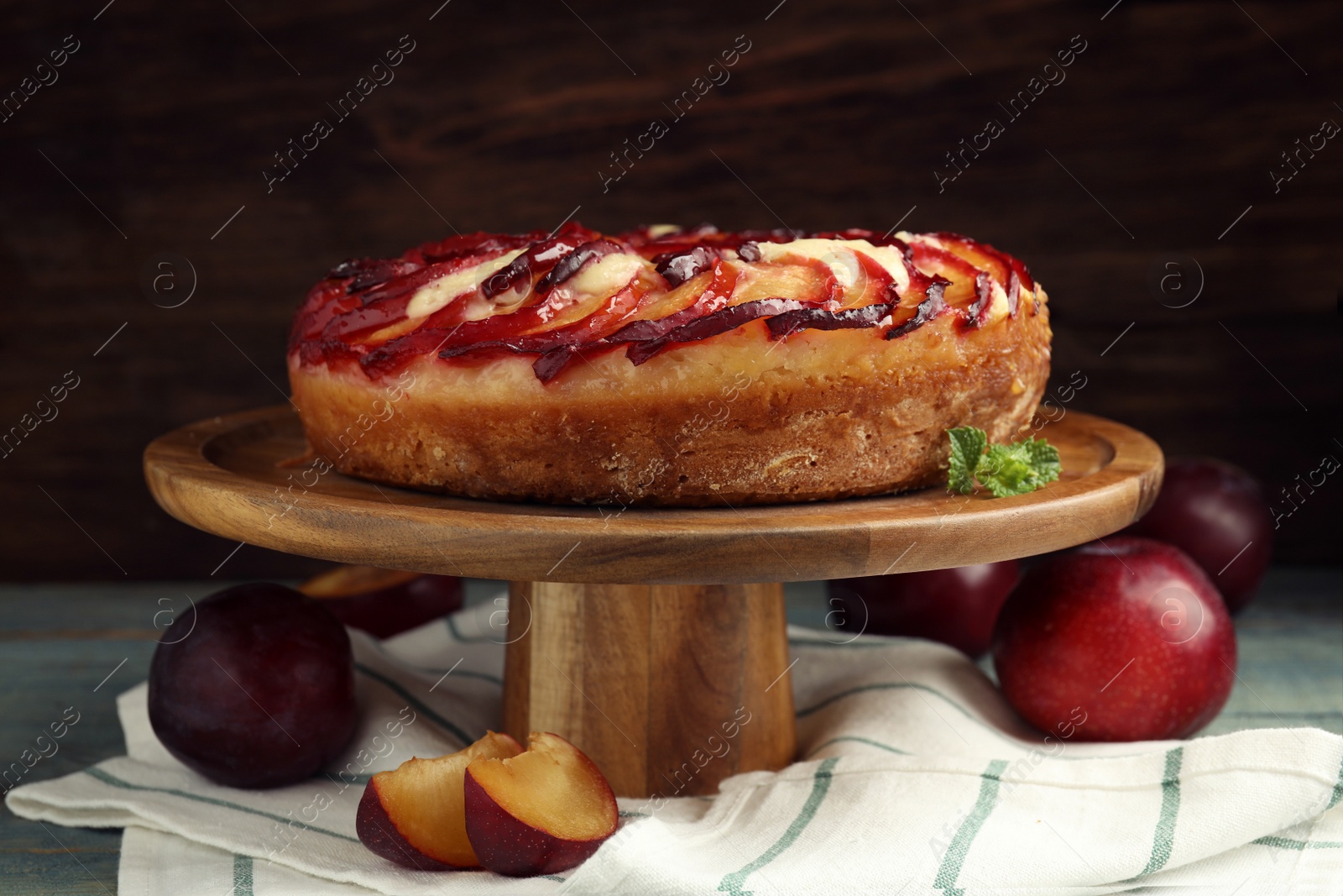 Photo of Delicious pie with plums on wooden cake stand