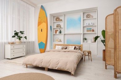 SUP board, bed and furniture in room. Interior design