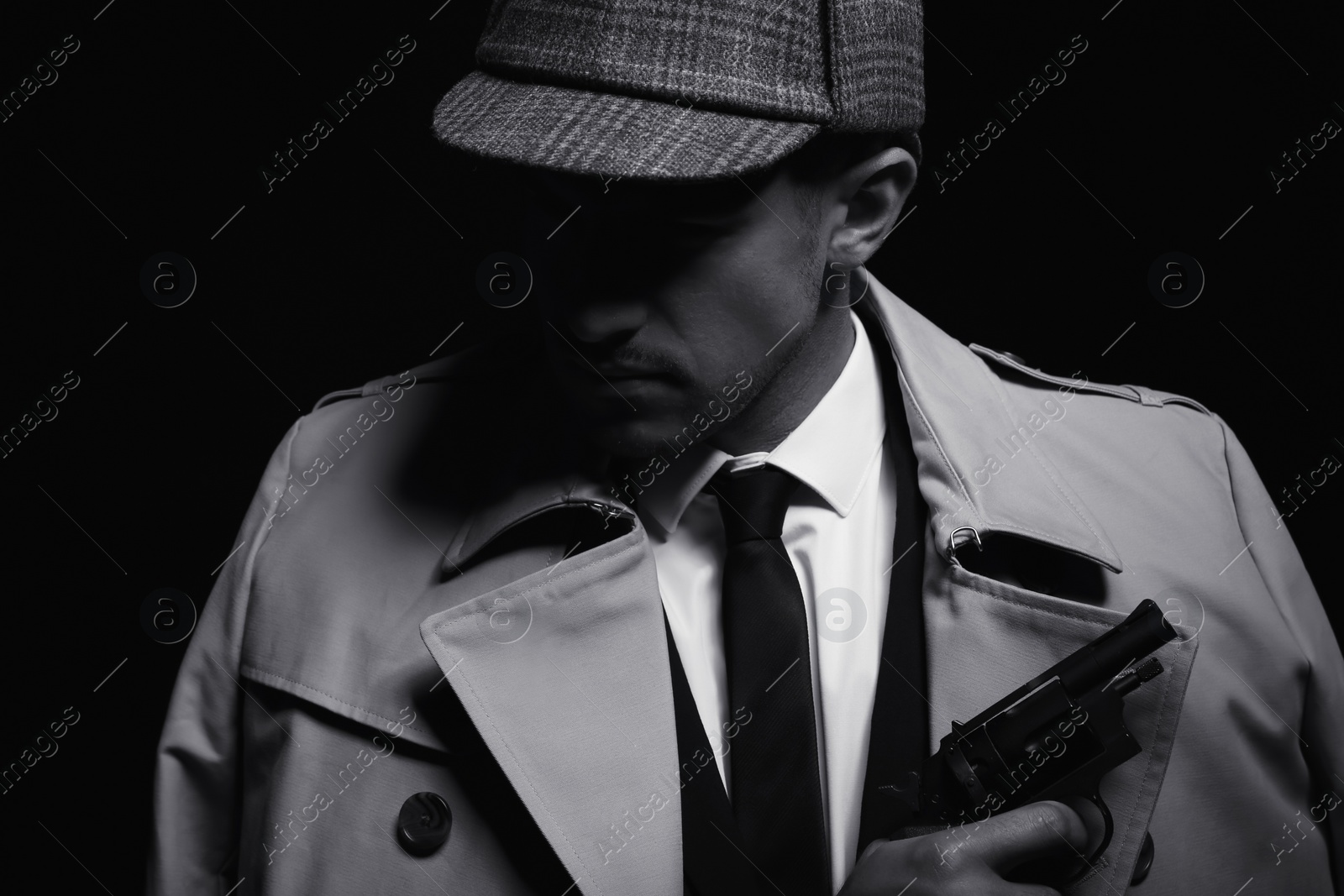 Photo of Old fashioned detective with revolver on dark background, black and white effect