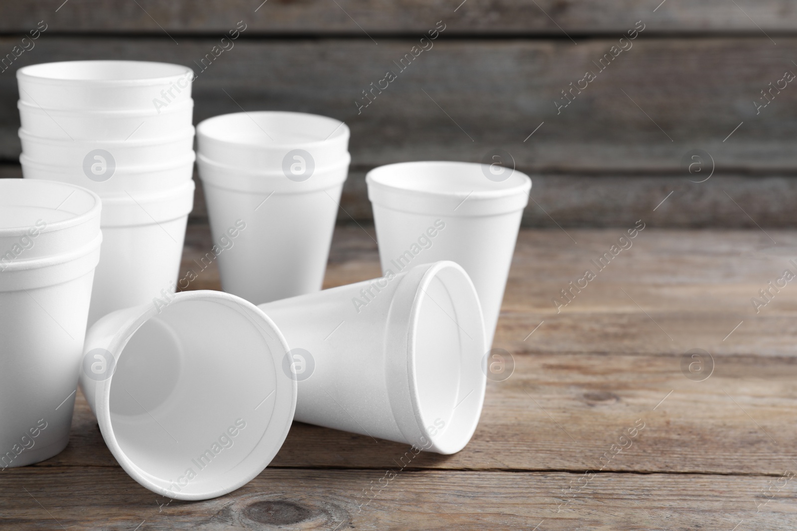 Photo of Many white styrofoam cups on wooden table, space for text