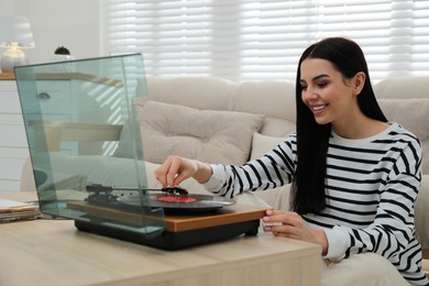 Photo of Woman listening to music with turntable at home