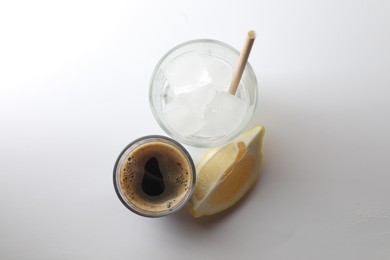 Coffee and ice cubes in different glasses, cut lemon on white background, top view