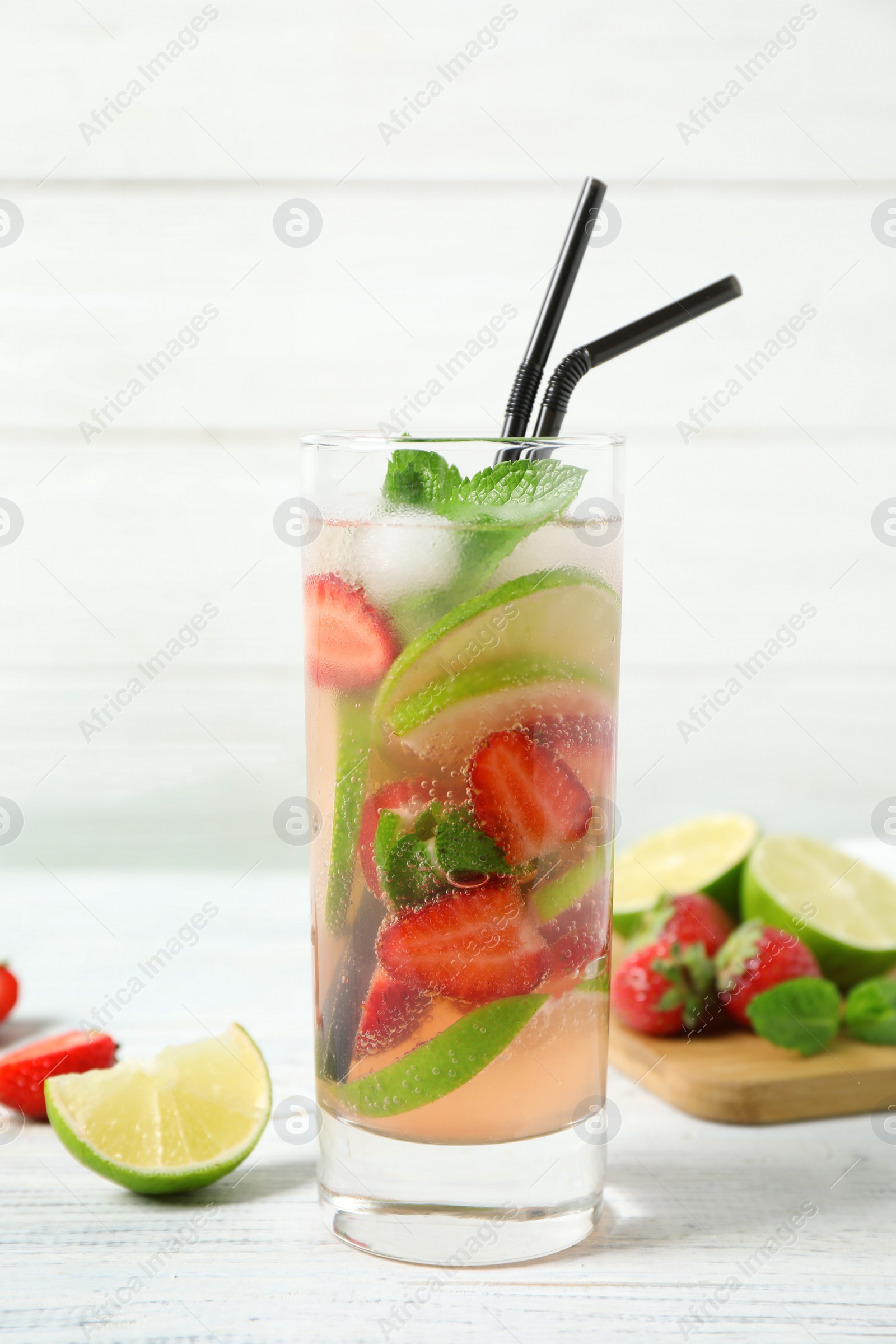Photo of Glass of delicious refreshing drink with strawberry and lime on white wooden table
