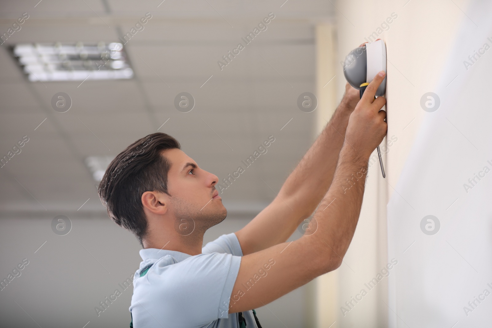 Photo of Technician installing CCTV camera on wall indoors