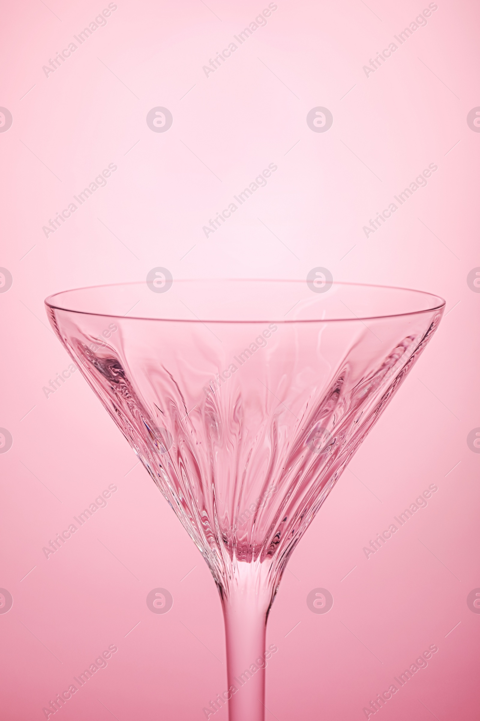 Photo of Elegant empty martini glass on pink background, closeup. Space for text