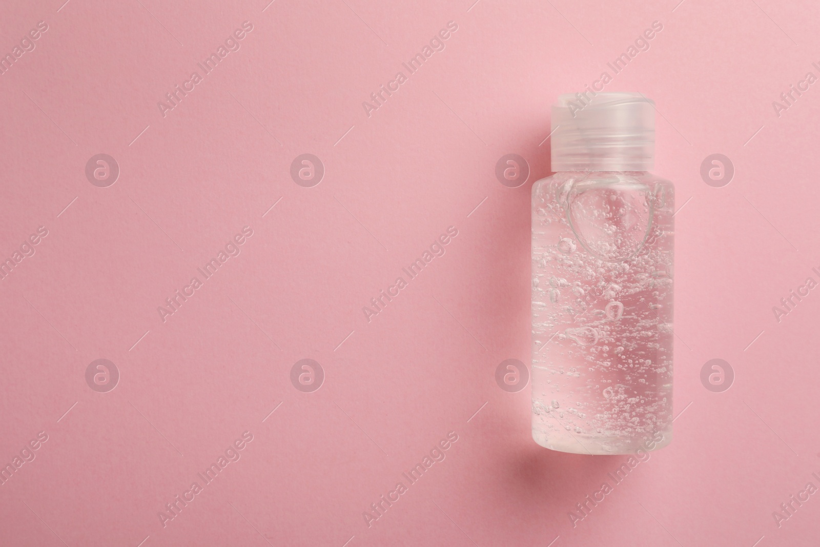 Photo of Bottle of cosmetic gel on pink background, top view. Space for text