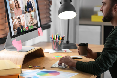 Image of Man having video chat with colleagues at table in office. Team work  