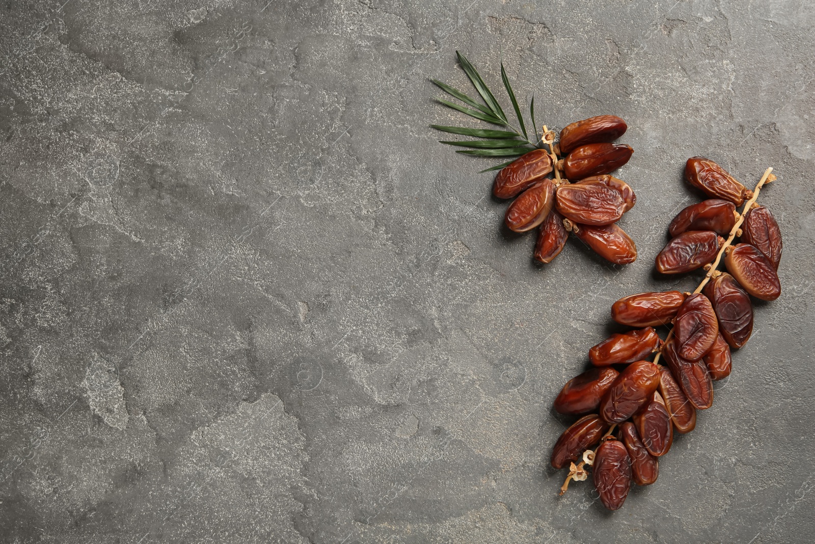 Photo of Branches with sweet dried dates on grey table, flat lay. Space for text