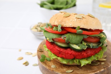 Photo of Tasty vegan burger with vegetables, patty and microgreens on white tiled table, closeup. Space for text