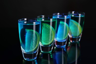 Photo of Alcohol drink with citrus wedges in shot glasses on mirror surface, closeup