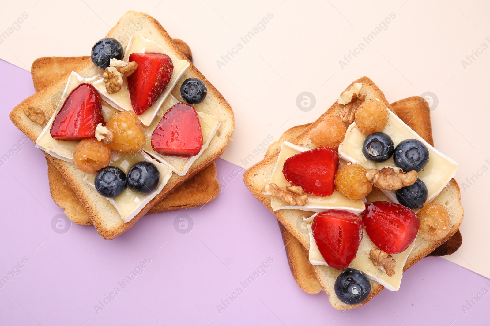 Photo of Tasty sandwiches with brie cheese, fresh berries and walnuts on color background, flat lay