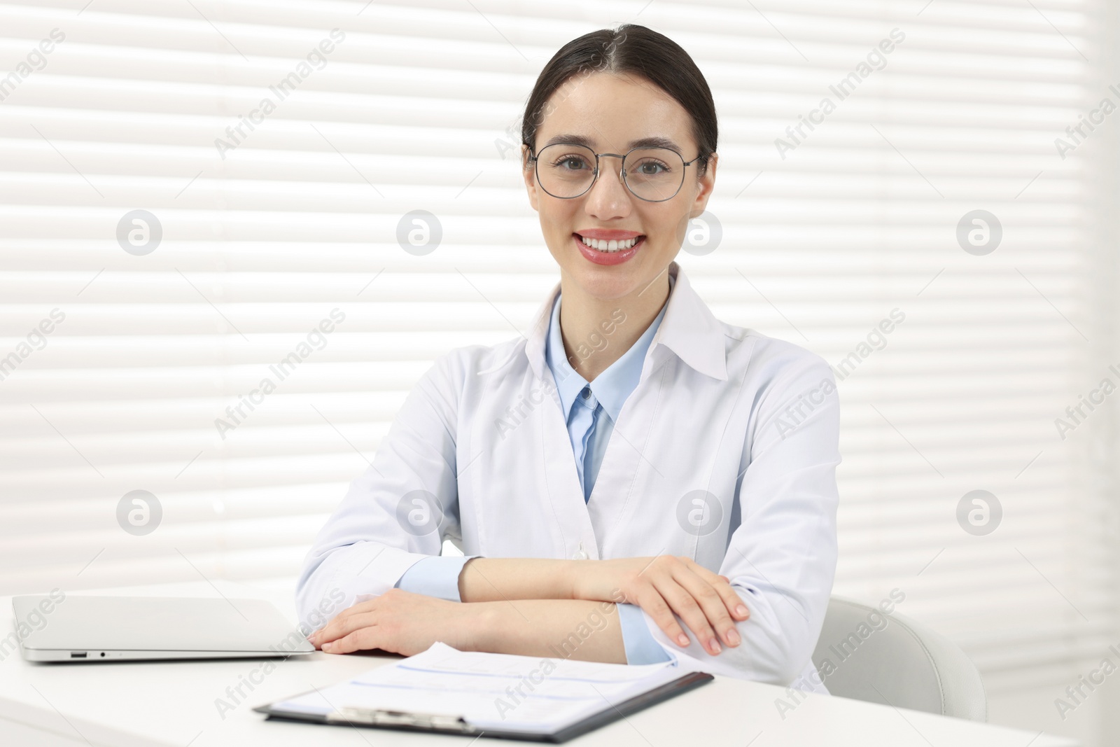 Photo of Medical consultant with glasses at table in clinic