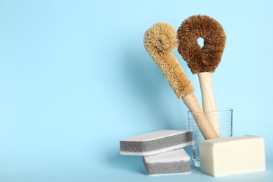 Photo of Cleaning brushes, sponges and soap bar light blue background, space for text. Dish washing supplies