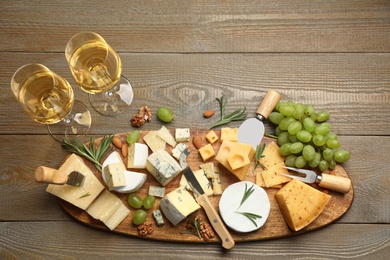 Photo of Flat lay composition with different sorts of cheese and knives on wooden table