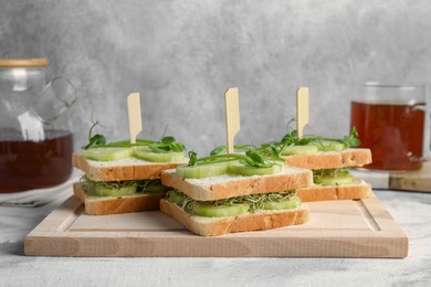 Tasty sandwiches with cucumber and microgreens on textured table