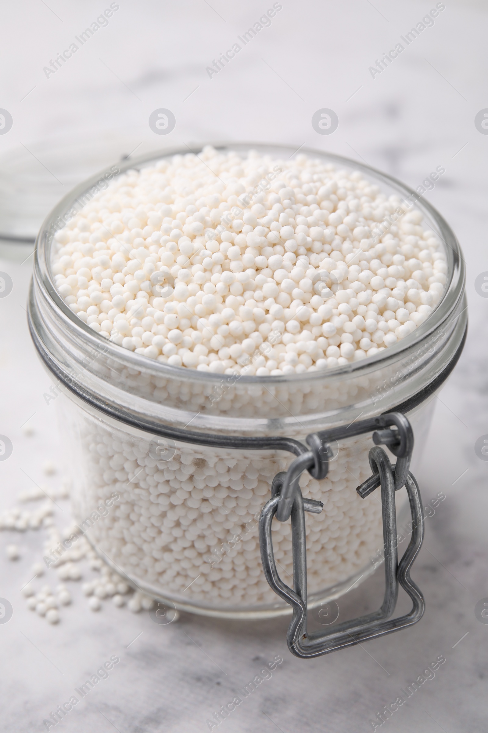 Photo of Tapioca pearls in jar on white table, closeup