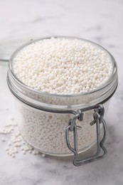 Photo of Tapioca pearls in jar on white table, closeup