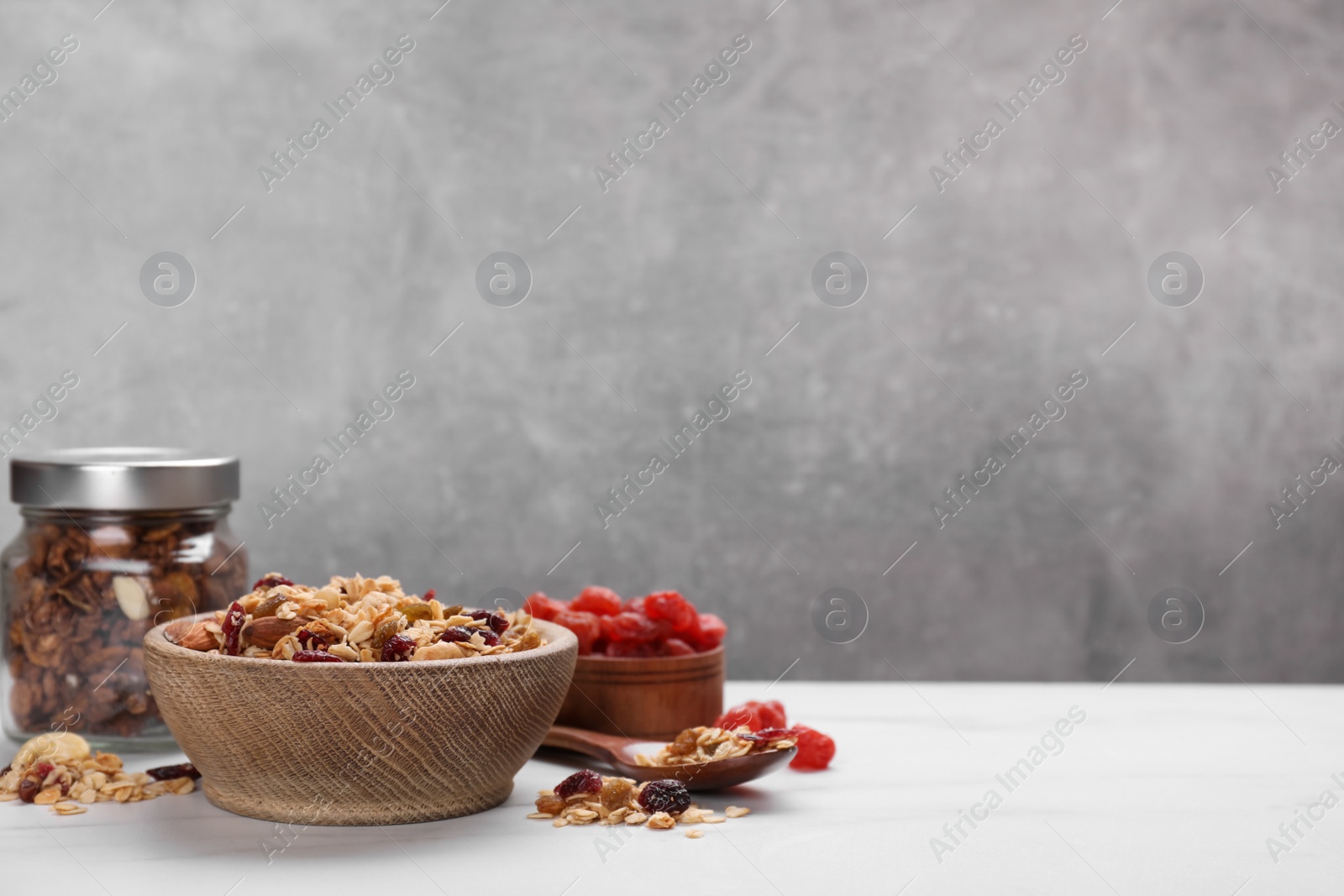 Photo of Tasty granola with nuts and dry fruits on white marble table. Space for text