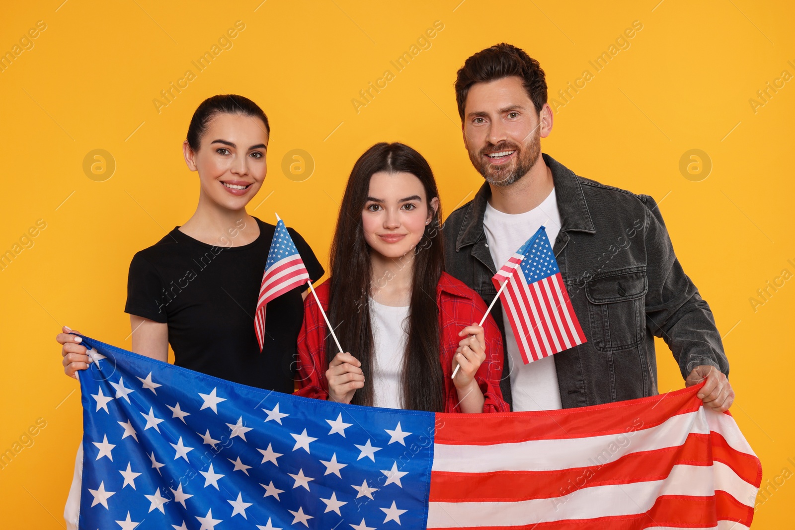 Photo of 4th of July - Independence Day of USA. Happy family with American flags on yellow background