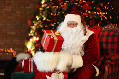 Santa Claus with gift sack near Christmas tree indoors