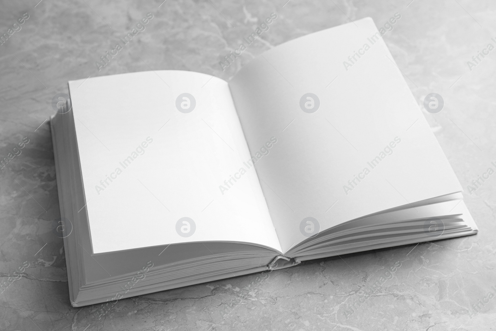 Photo of Open book with blank pages on light grey marble background. Mock up for design