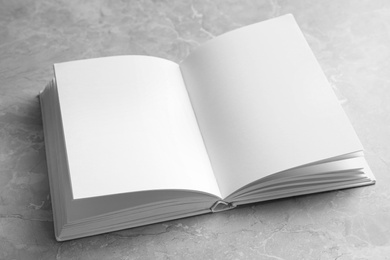 Photo of Open book with blank pages on light grey marble background. Mock up for design