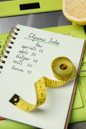 Notebook with products of low glycemic index, calculator, measuring tape and lemon, closeup