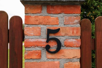 Photo of House number 5 on red brick column outdoors