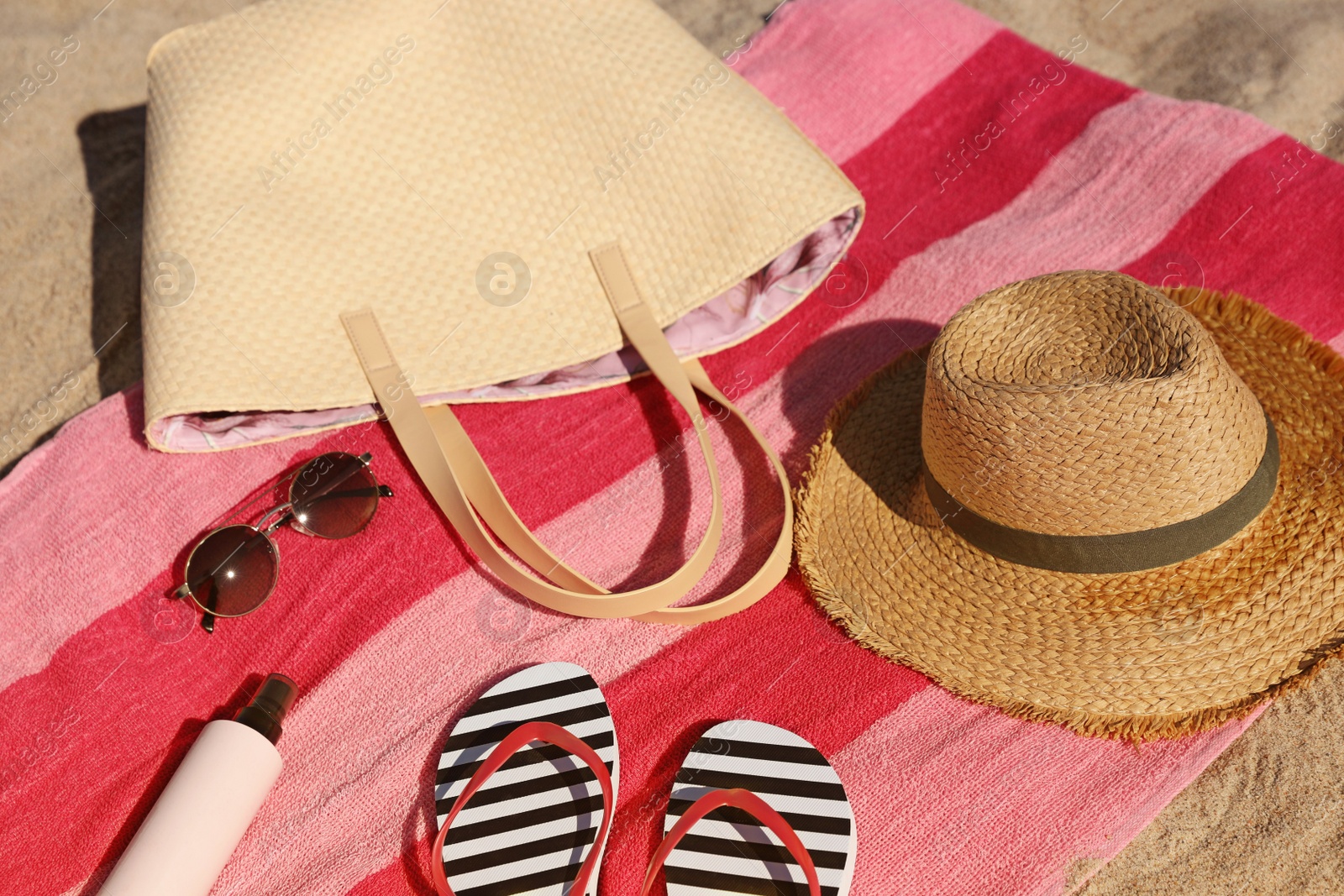 Photo of Straw hat, bag and other beach items on sand, closeup