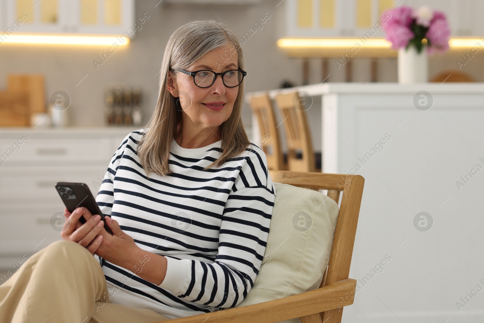 Photo of Senior woman using mobile phone at home, space for text