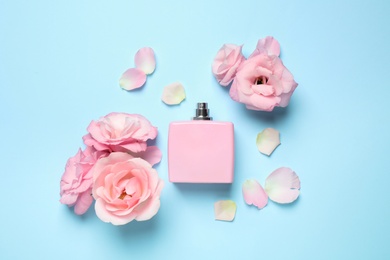 Photo of Flat lay composition with bottle of perfume and flowers on light blue background