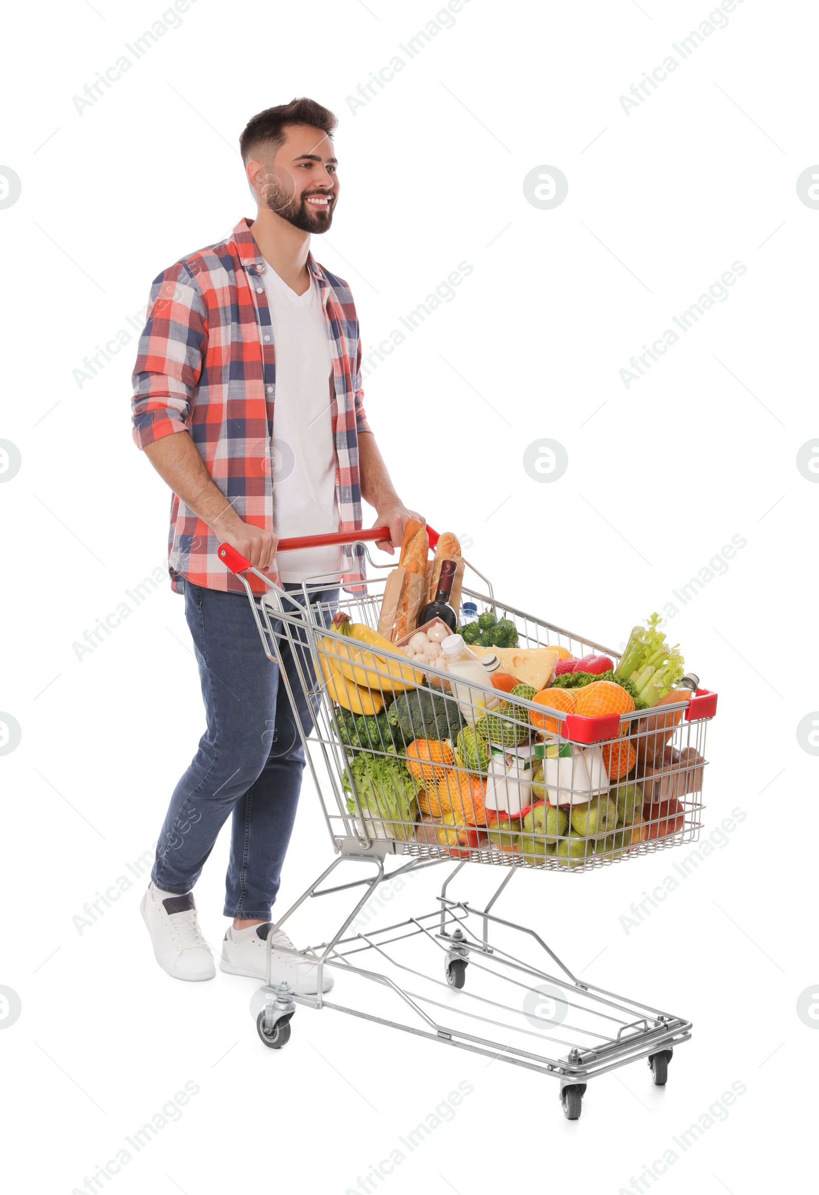 Photo of Happy man with shopping cart full of groceries on white background