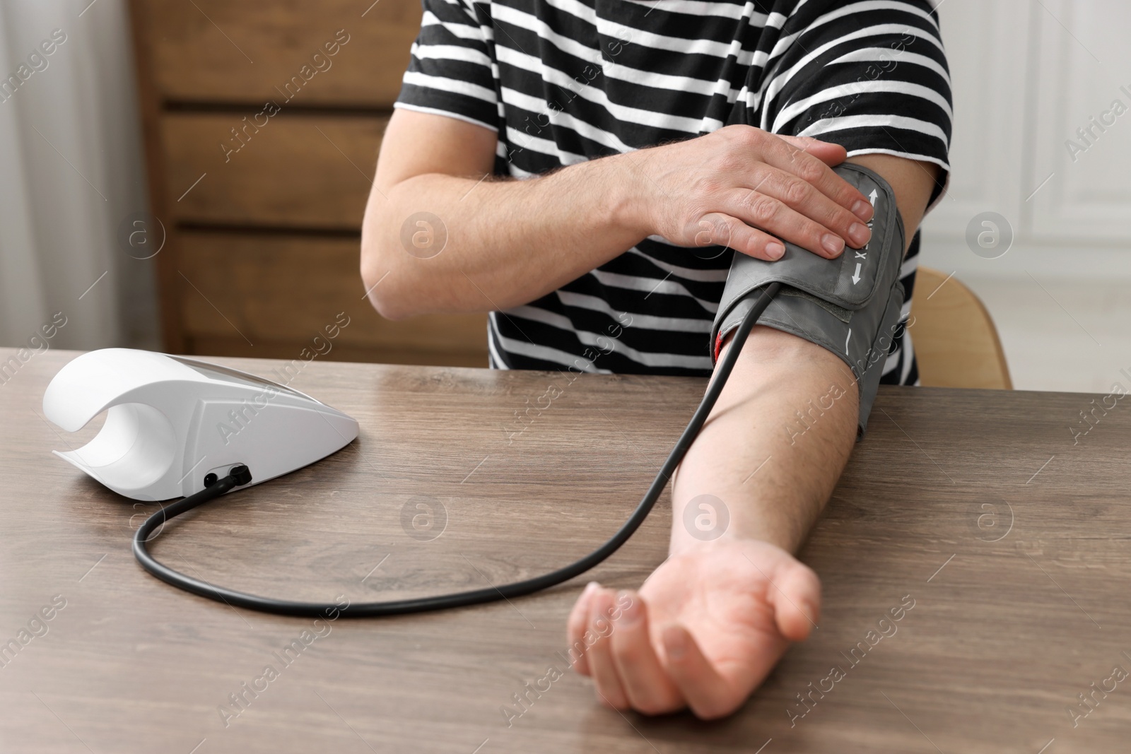 Photo of Man measuring blood pressure in room, closeup