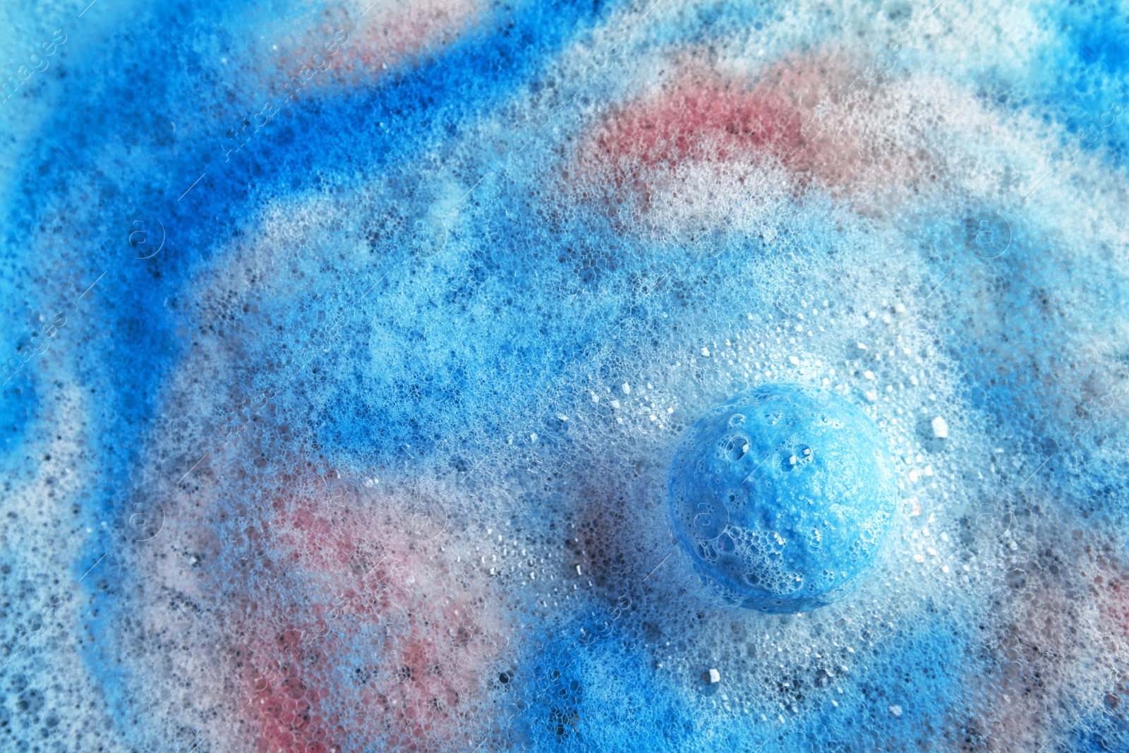 Photo of Dissolving color bath bomb in water, top view. Space for text