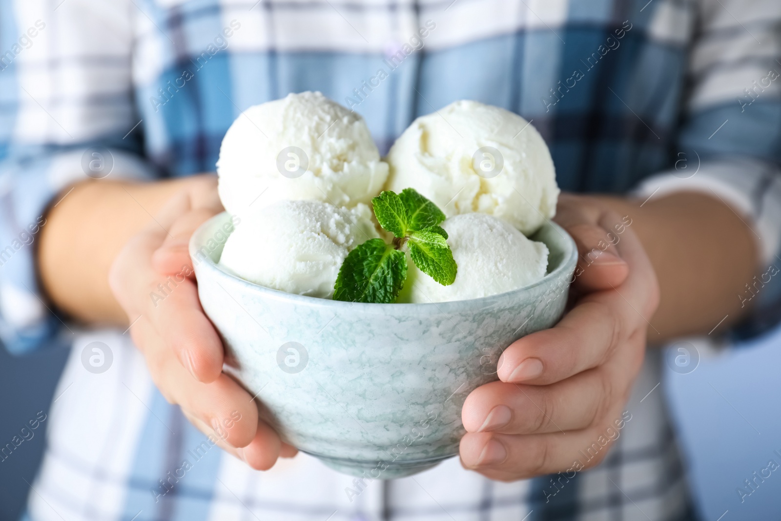 Photo of Woman holding bowl full of ice cream with mint, closeup