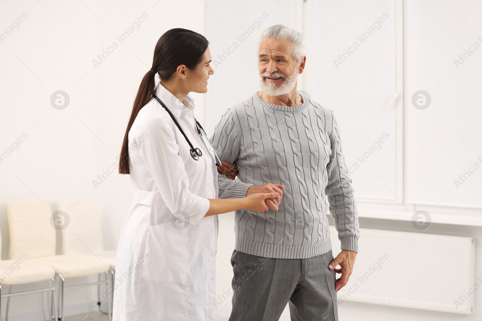 Photo of Smiling nurse supporting elderly patient in hospital