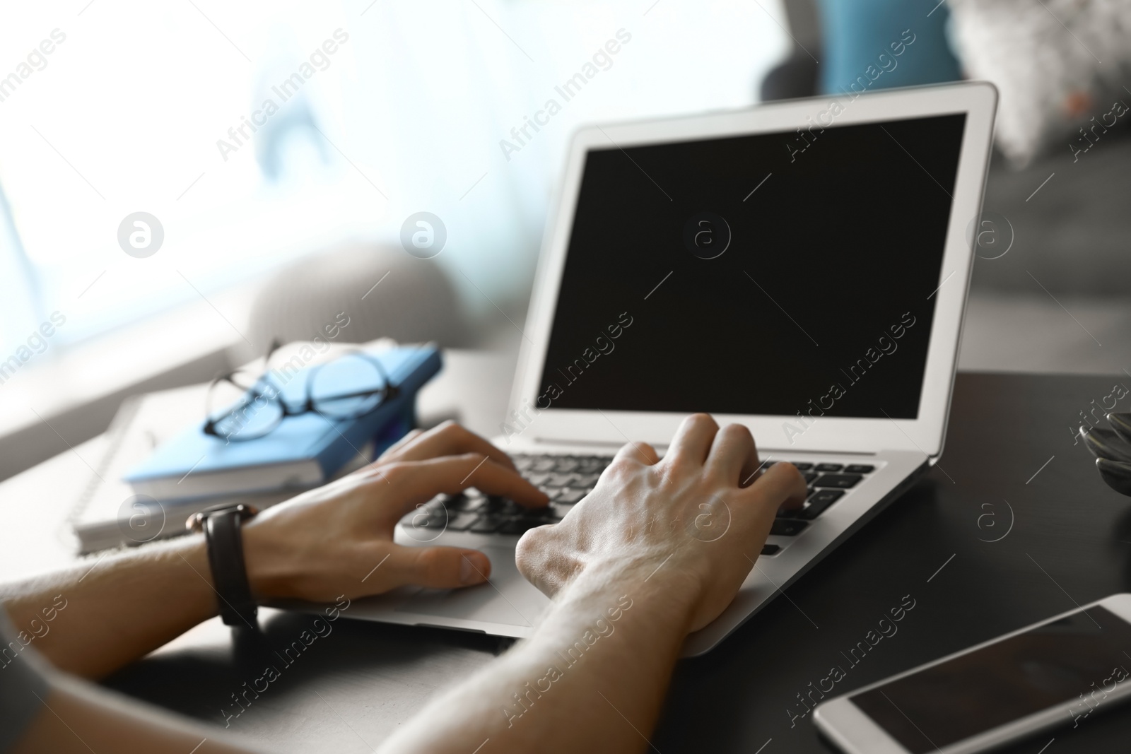 Photo of Man using laptop at table indoors, closeup. Space for text