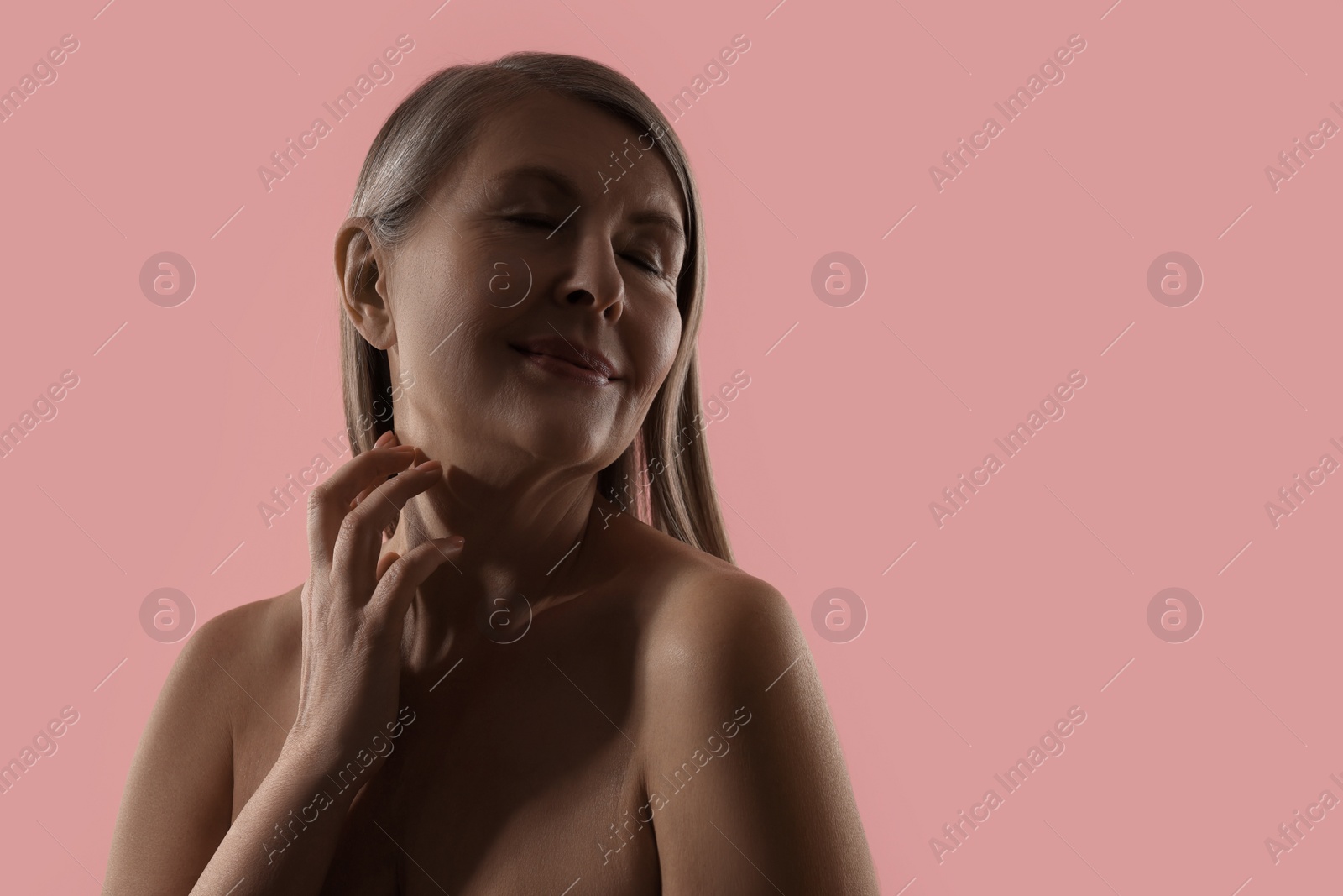 Photo of Beautiful woman touching her neck on pink background, space for text