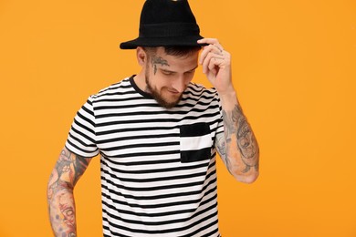 Photo of Handsome hipster man wearing stylish hat on orange background