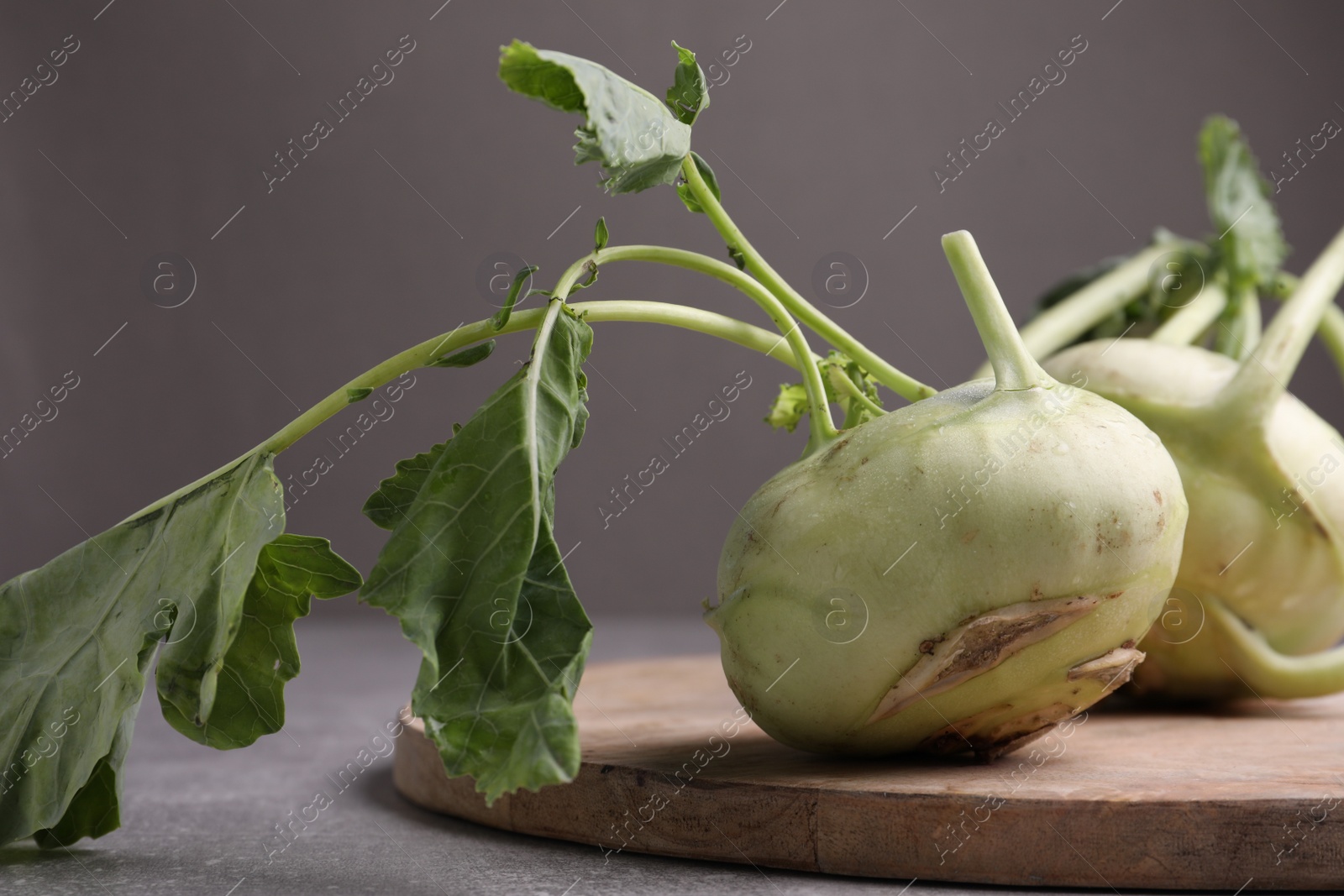 Photo of Whole ripe kohlrabi plants on grey table, closeup