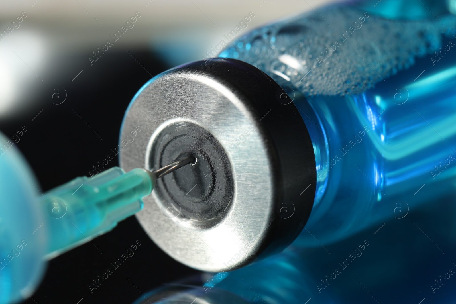 Photo of Filling syringe with medicine from vial on table, closeup