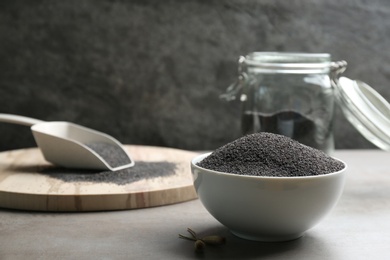 Photo of Poppy seeds in bowl on grey table. Space for text