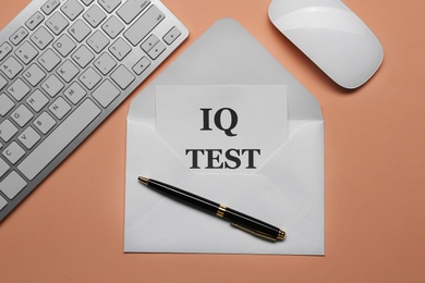 Photo of Note with text IQ Test in envelope, keyboard and mouse on coral background, flat lay