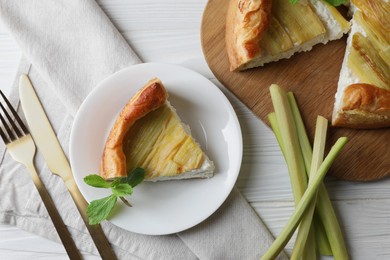 Photo of Freshly baked rhubarb pie, stalks and cutlery on white wooden table, flat lay