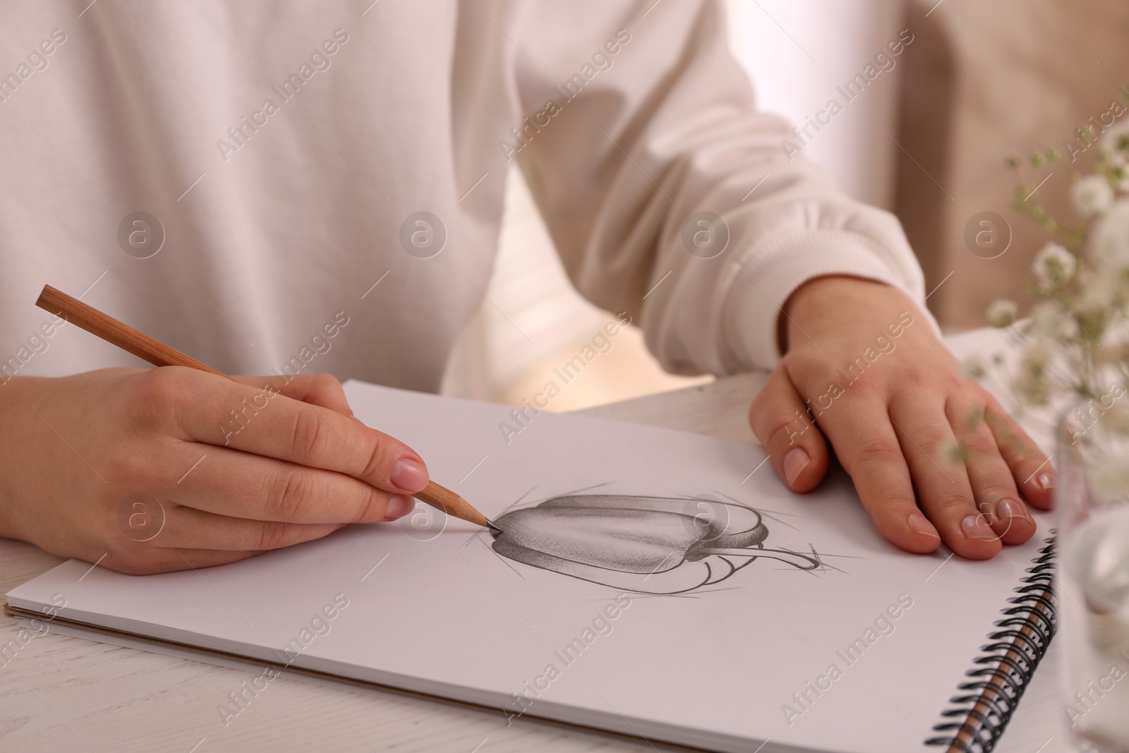 Photo of Woman drawing bell pepper with graphite pencil in sketchbook at table, closeup