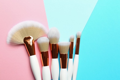 Many different makeup brushes on color background, flat lay. Space for text