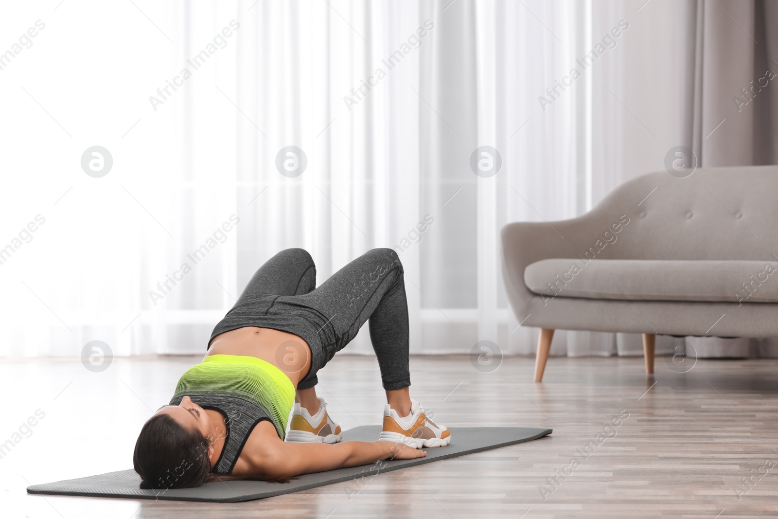 Photo of Young woman in fitness clothes doing exercise at home. Space for text