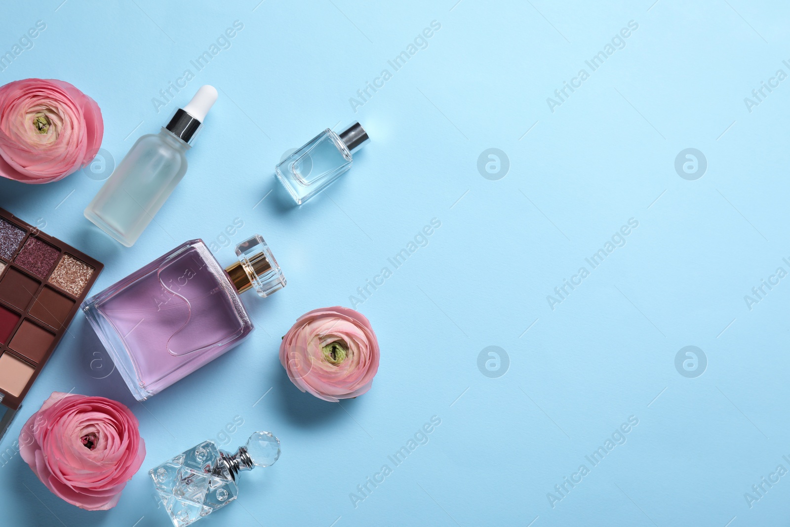 Photo of Flat lay composition with different makeup products and beautiful spring flowers on light blue background, space for text