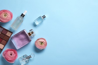 Flat lay composition with different makeup products and beautiful spring flowers on light blue background, space for text